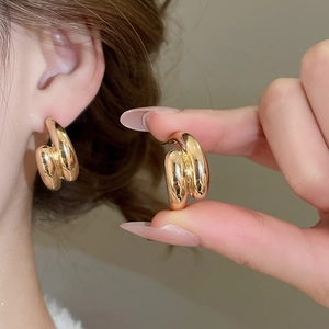 Close-up of polished gold double-layered U-shaped drop earrings worn by a model