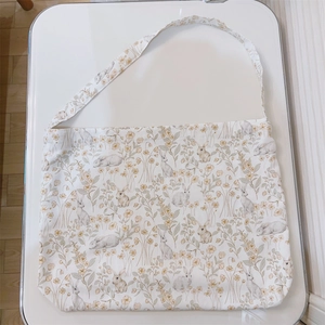 Detail view of cotton floral rabbit pattern on cream-colored canvas crossbody bag