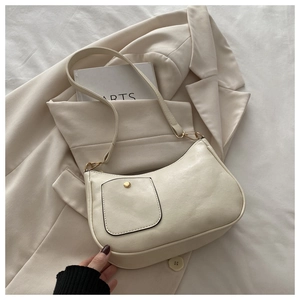 Detail of minimalist beige PU leather shoulder bag with a gold buttoned front pocket