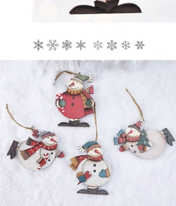 Detail of four colorful wooden snowman ornaments with rustic twine hangers on snow backdrop