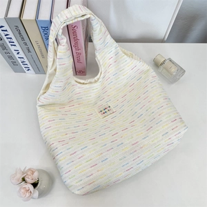 Flat lay of cream knit tote bag with colorful texture and sozakka beauté label
