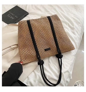 Detail of woven straw tote bag with black rope handles and knotted decoration