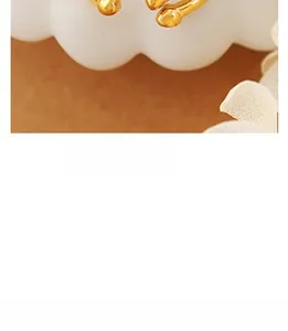 Detailed close-up of a golden twist ring with polished spherical ends in minimalist style