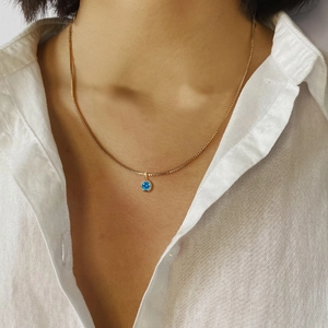 Detailansicht einer zierlichen Goldkette mit blauem runden Steinhänger am Modell