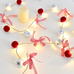 Christmas LED garland with red pom-poms, snow bells, and warm lighting on a white background