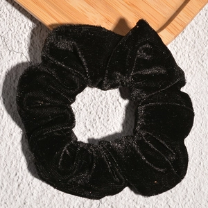 Close-up of black velvet scrunchie showing premium soft fabric texture and pleated design