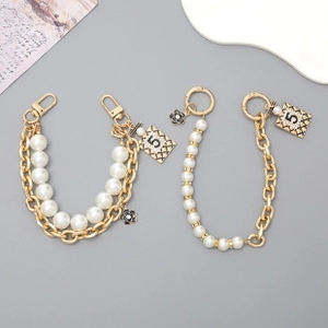 Detail of luxury pearl purse chain with gold number 5 charm and black camellia flower