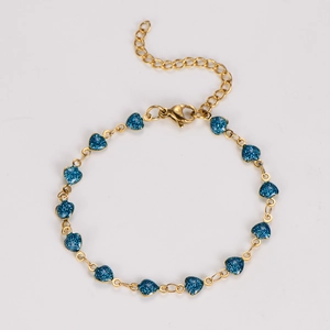 Detail of gold chain bracelet featuring dark blue glitter heart pendants with lobster clasp