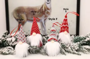 Set of four knitted Christmas gnomes with red and grey patterns hanging on a snowy tree