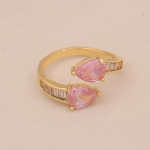 Détail de zircons roses sur une bague ajustable dorée avec accents de baguettes