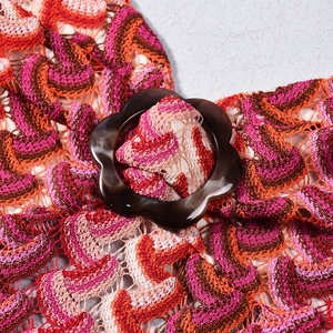 Detail of colorful wave knit pattern with a decorative brown resin floral button