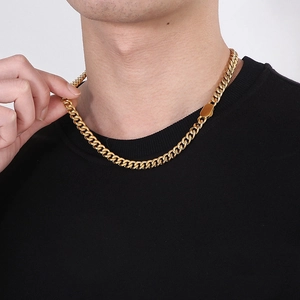 Detail of a thick gold Cuban link chain worn by a man, showing metal texture and fit