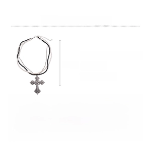 Detailed view of triple-layer cross pendant with glass pearls and sparkling rhinestones