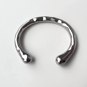 Bracciale rigido aperto argento lucido con texture martellata irregolare minimalista