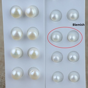 Macro detail of natural white freshwater button pearls set on a white display card