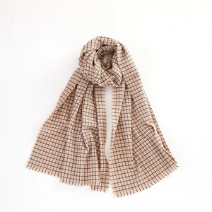 Detailed view of beige houndstooth scarf featuring soft wool texture and fringe trim