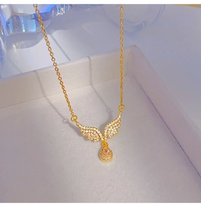 Macro shot of gold angel wing pendant with pink teardrop gemstone in jewelry box