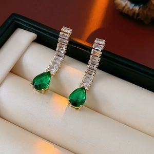 Detail view of gold drop earrings with green teardrop stones in a jewelry gift box