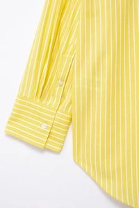 Detail of yellow and white striped shirt with high-density cotton texture and buttoned cuff