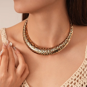 Detail shot of a golden leopard print U-shaped rigid collar necklace on a female model