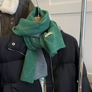 Detail of green and grey double-sided knitted scarf with a beige hand-made woven label