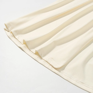 Dettaglio dell'orlo pieghettato dei pantaloni in maglia crema con trama del tessuto