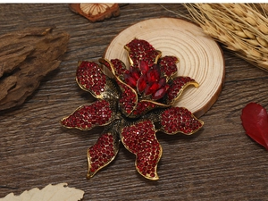 Close-up of vintage flower brooch with red rhinestones on a rustic wooden background
