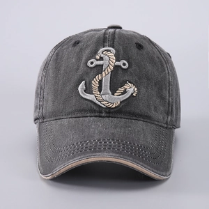 Detail of anchor embroidery on washed dark grey cotton baseball cap with vintage texture