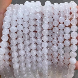 Close-up of hand holding natural white jade round beads for jewelry making
