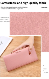 Close-up of pink leather texture and a long tri-fold wallet held by hand on a wooden table