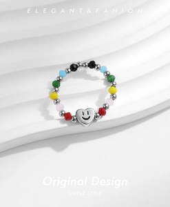 Vue détaillée d'une bague perlée colorée avec un pendentif cœur souriant sur un support
