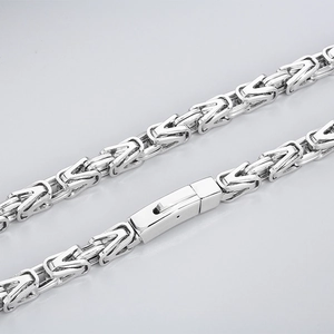 Close-up of silver Byzantine chain links with a secure box clasp on a neutral background