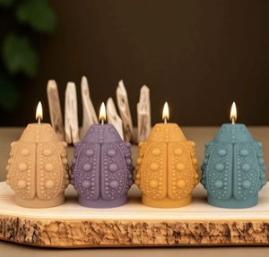 Detail view of four colored beetle-shaped candles with textured surface on a wooden tray