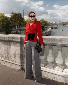 Detail of red slim blazer with a black bow waist decoration and textured wool fabric