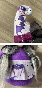 Detail of bat pattern on hat and lace hem of Halloween purple faceless gnome doll