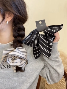 Detail of striped bow scrunchies with long ribbons on braided hair and hand held view