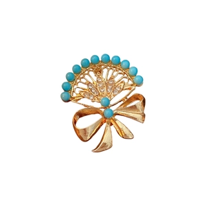 Vintage gold fan brooch with blue beads and bow ribbon design on white backdrop