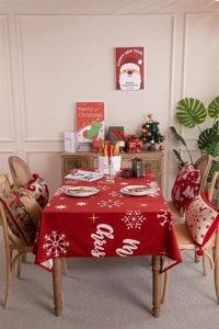 Detail view of festive red Christmas tablecloth with white snowflakes and Merry Christmas text