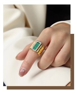 Macro detail of gold-plated signet ring with green malachite stone and diamond-set halo