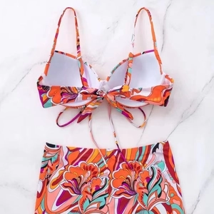 Two-piece floral graffiti bikini set with halter top and high-waisted shorts on marble