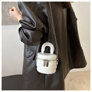 Vue détaillée d'un mini sac cylindre blanc avec chaîne argentée et poignée ronde