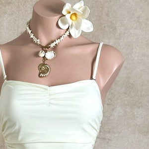 Close-up of ocean-themed shell necklace with gold accents on a beige camisole top