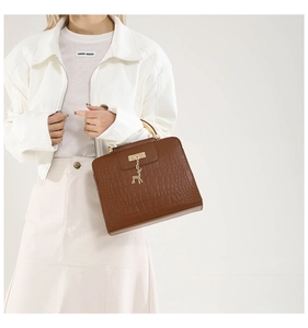 Detailed side view of brown faux crocodile leather bag with gold semi-circular handle