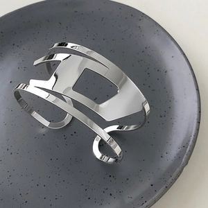 Macro view of silver hollowed D-shaped metal cuff bracelet with mirror-polished finish