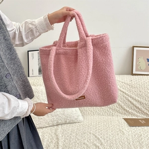 Detail of pink teddy faux fur tote bag featuring a brown leather brand label and soft texture