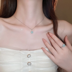 Close-up of model wearing silver necklace and ring with square blue stones and diamonds