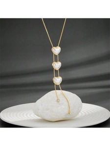 Macro detail of gold necklace with white heart pendants and zircon tassels on marble