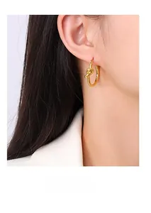 Close-up of elegant gold knotted hoop earrings worn by a model in a minimalist style