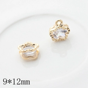 Macro detail of 9x12mm gold flower pendants with clear zircon for DIY jewelry making