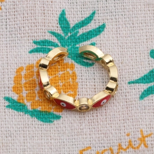 Macro shot of gold adjustable ring with red enamel evil eye and micro zircon inlay